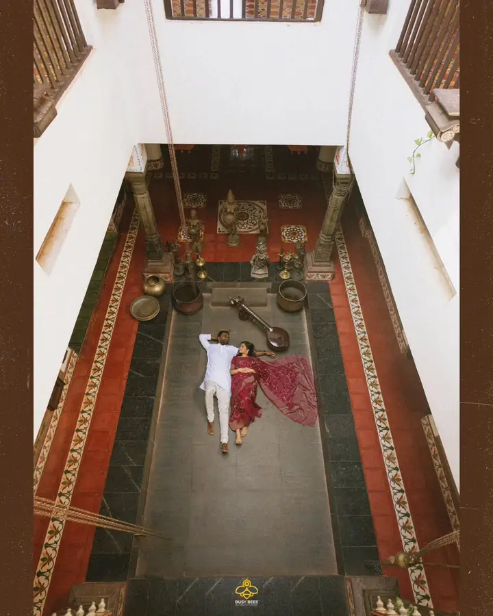 Abhijith & Chinnu: overhead frame of the couple lying in the open courtyard of a traditional nalukettu