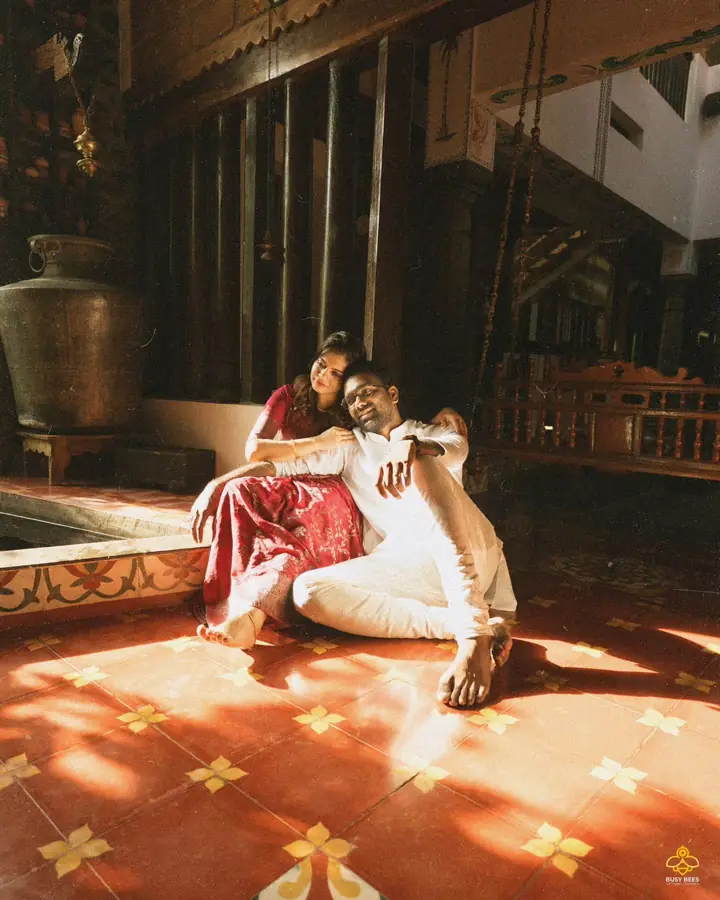 Abhijith & Chinnu: couple resting on a sunlit veranda beside a brass urali in a heritage home