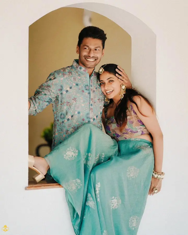 Abhijith & Chinnu: couple in matching teal seated in an arched alcove, laughing