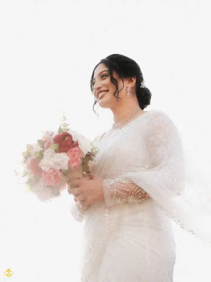 Abhijith & Chinnu: bride in a white lace saree holding a pink and white bouquet