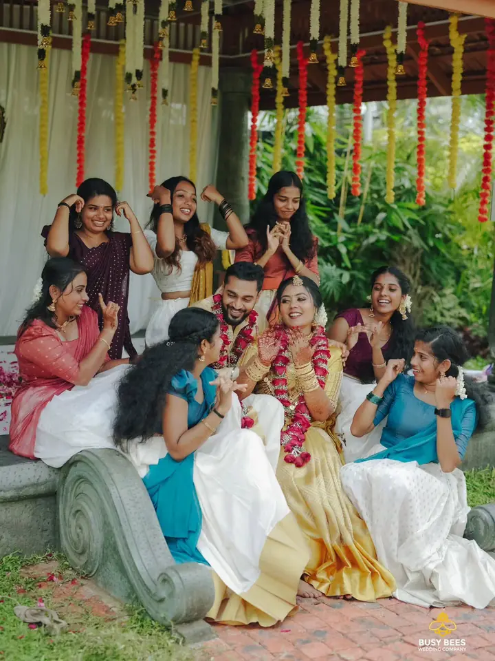 The garlanded couple with friends under strings of marigold at a home ceremony