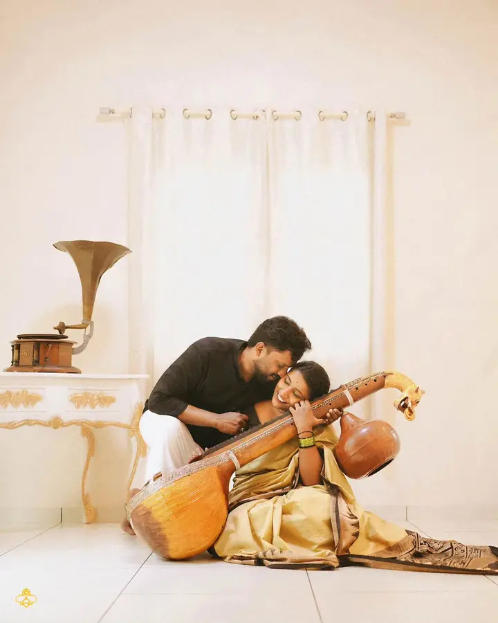 Groom leans over the bride as she holds a veena beside an old gramophone