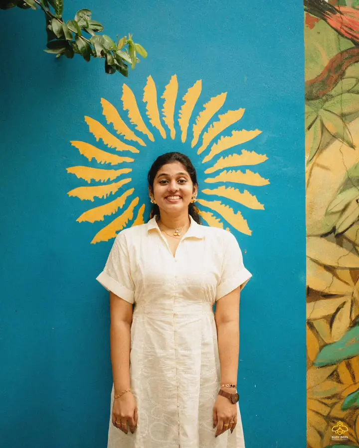 Portrait in a white shirt against a teal mural with a painted gold sunburst