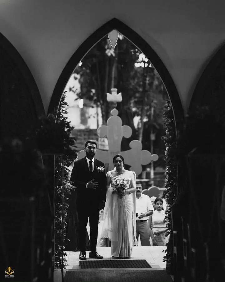 Black and white frame of the couple leaving the church through a gothic arch