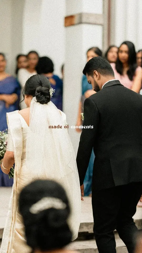 Guests look on as the bride in white and the groom walk into the church