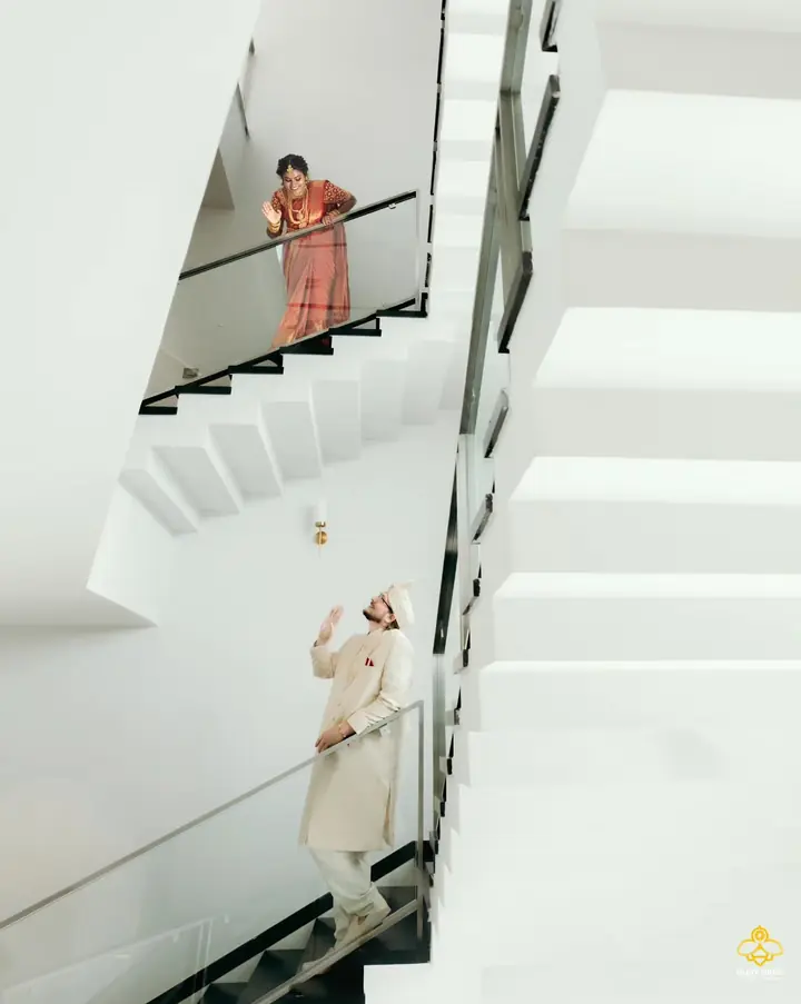 The bride comes down a bright white staircase as the groom waits below
