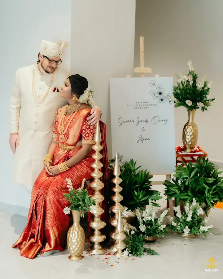 Couple seated at their engagement backdrop between tall brass lamps