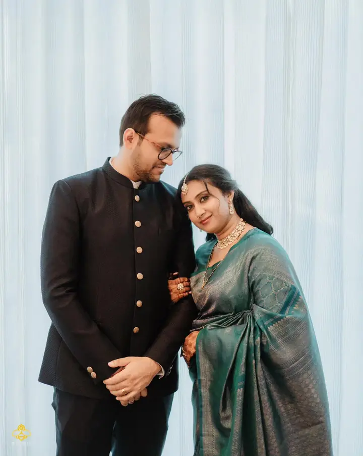 Couple in a black bandhgala and teal silk saree in soft curtain light