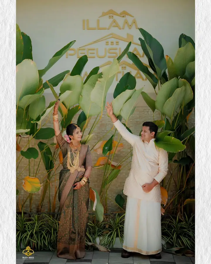 Couple raise their arms together in front of a leafy backdrop